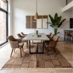 Pink geometric Moroccan wool rug in modern dining room with concrete table and upholstered chairs