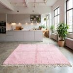 Blush pink Moroccan wool rug with grid pattern in bright kitchen with white cabinets and plants