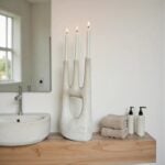 Handcrafted white ceramic candle holder with hand-shaped design in contemporary bathroom setting