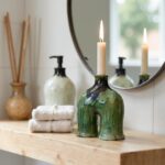 Artisanal green ceramic candle holder featuring drip glaze finish and unique arch shape with lit taper candle