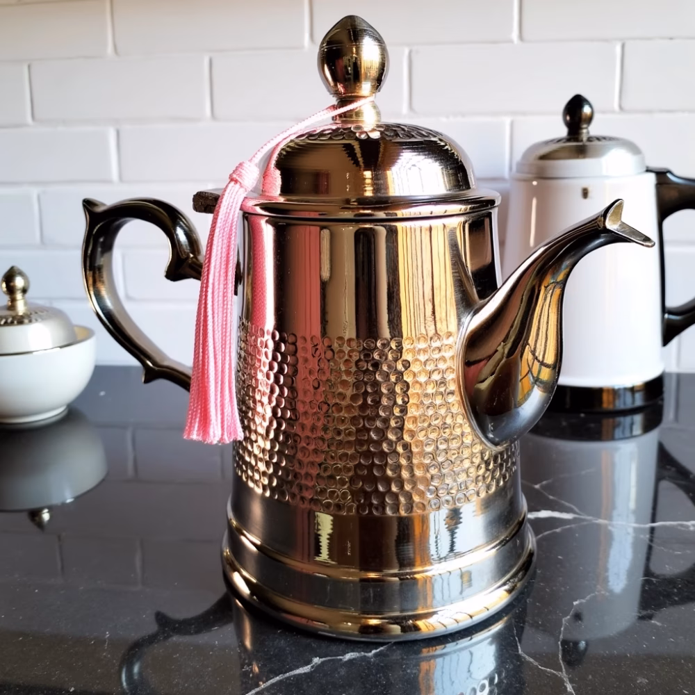 Moroccan brass coffee pot with silver plating against white wall