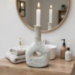 Tamegroute ceramic candle holder in bathroom, weathered gray pottery with towels and round mirror