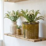 Handmade Moroccan ceramic planters in three sizes with ribbed design arranged on floating wooden shelves with vases