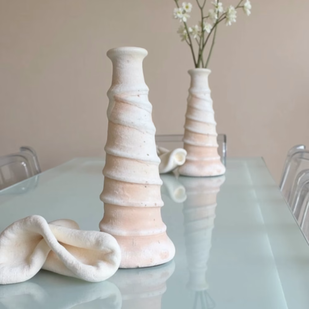 Pair of white ceramic candle holders on glass table