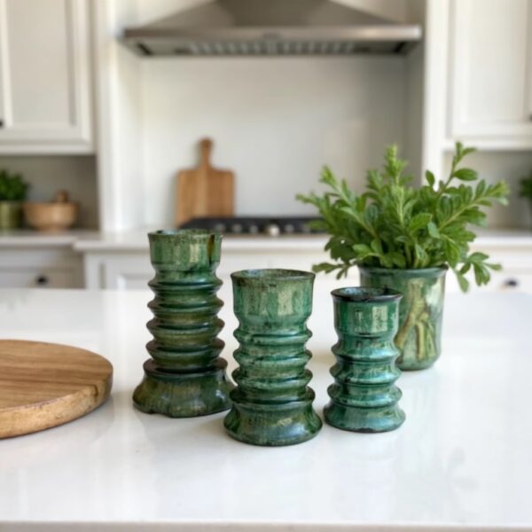 Three stacked ceramic candleholders set in green Tamegroute glaze displayed in modern white kitchen with herbs