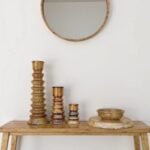 Graduated ceramic candleholders set in golden glaze on wood console table with brass mirror and wooden bowl