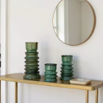Set of three green candleholders on wooden console table