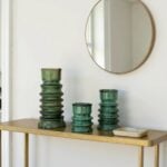 Green glazed ceramic candleholders set of 3 with sculptural stacked design on gold console beneath round mirror