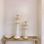 Set of two white tiered column candleholders on wooden bench