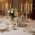 Elegant silver coffee server set as centerpiece on formal dining table with silver candelabras, crystal glassware, and fine bone china