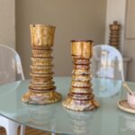 Close-up of handmade ceramic candleholders set in distressed gold glaze showing artisan stacked pillar detail