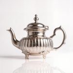 Handcrafted ribbed silver teapot with elegant fluted design and ornate decorative feet on studio background