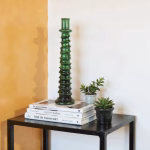 Tall candle holder in green against golden wall
