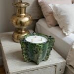 Decorative ceramic candle 10 inch piece in signature green glaze on bedside table