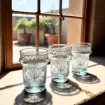 Traditional hand-painted tea glasses by window showing pattern detail