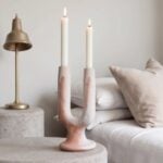 Pink marble glazed ceramic candle holder twin arc Y-shaped design with lit candles on bedside