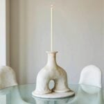 Handcrafted ceramic candleholder with arch design on glass table, white speckled finish statement piece
