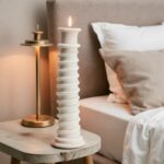 Handmade white ceramic candle holder with sculptural spiral design near window with pampas