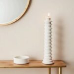 White handcrafted ceramic candle holder with spiral grooves and lit candle on wooden table