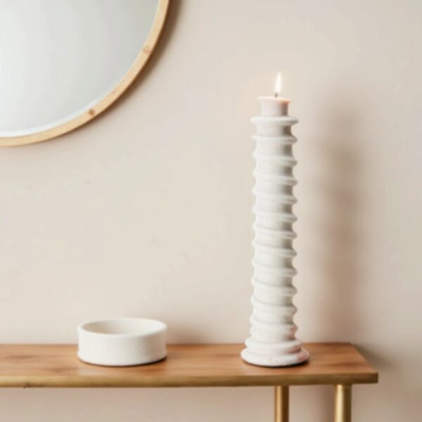 White handcrafted ceramic candle holder with spiral grooves and lit candle on wooden table