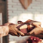 Person giving a beautifully wrapped handmade gift, representing the art of mindful gift-giving