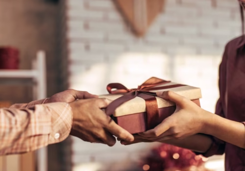 Person giving a beautifully wrapped handmade gift, representing the art of mindful gift-giving