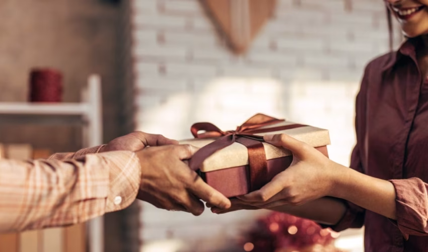 Person giving a beautifully wrapped handmade gift, representing the art of mindful gift-giving