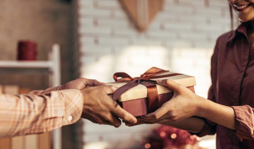 Person giving a beautifully wrapped handmade gift, representing the art of mindful gift-giving