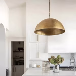 Brass dome pendant light illuminating white contemporary kitchen.