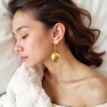 Woman wearing hammered brass earrings in elegant bridal setting showcasing golden textured finish