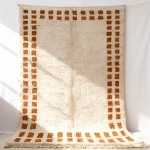Close-up detail of handwoven border rug showing geometric pattern and fringe edges in cream and brown