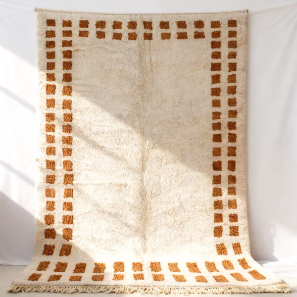 Close-up detail of handwoven border rug showing geometric pattern and fringe edges in cream and brown