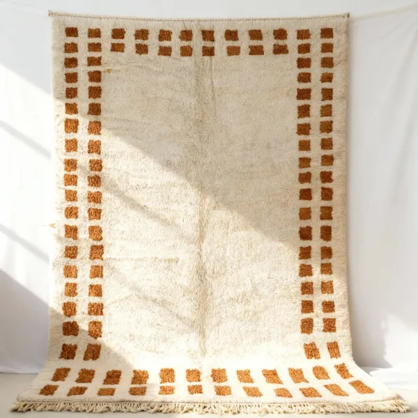 Close-up detail of handwoven border rug showing geometric pattern and fringe edges in cream and brown