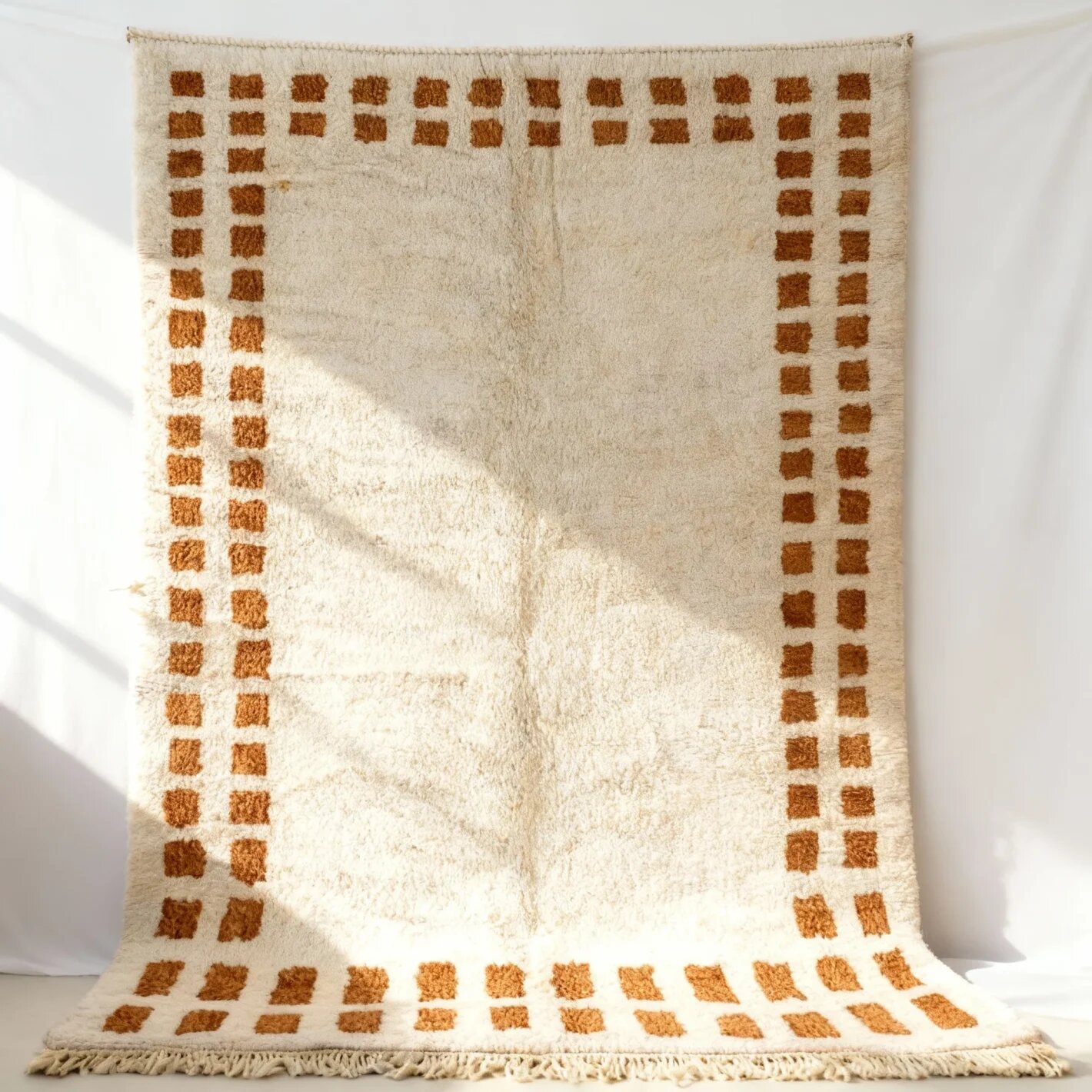 Terracotta border wool rug close-up detail - MCWR25 (Featured Close-Up) Terracotta border wool rug with geometric Berber pattern, cream high-pile texture, and fringe detail against white wall