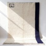 Modern wool rug with cream high-pile texture, navy border, and Greek key corner detail in minimalist style
