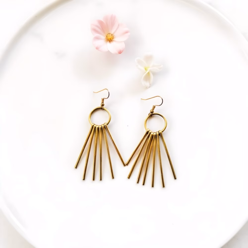 Gold fringe earrings with stick design on white background