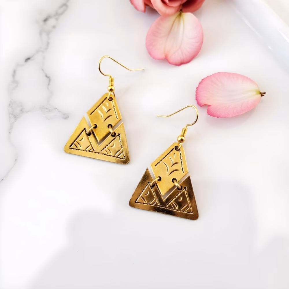 Gold triangle earrings with engraved design on marble