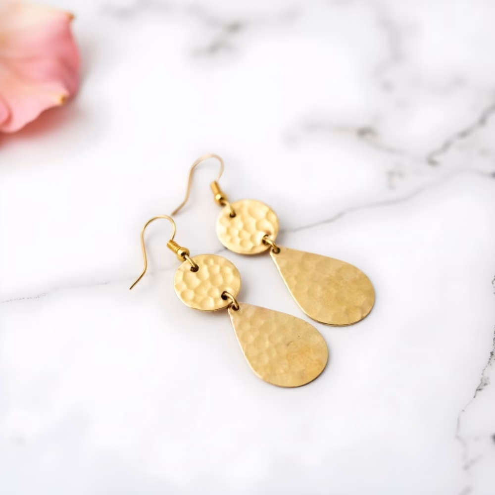 Handmade gold teardrop earrings on marble surface