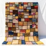 Patchwork color block rug handwoven with vibrant multicolor wool squares separated by black lines and fringe edges