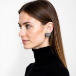 Woman wearing sterling silver half circle earrings with geometric striped design, side profile view