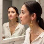 Side view of brass fringe earrings with antique gold finish and sunburst stick drop design on model