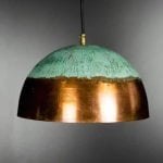 Illuminated hand-hammered brass pendant light showcasing verdigris and copper dome craftsmanship detail