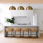 Three brass dome pendant lights over kitchen island with bar stools