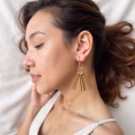 Woman wearing gold fringe earrings in natural light