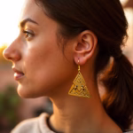 Woman wearing gold triangle earrings at sunset