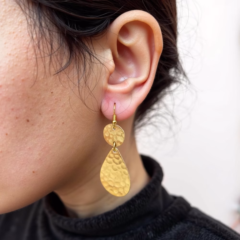 Woman wearing hammered gold drop earrings side view