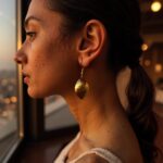 Close-up of hammered brass earrings at golden hour displaying warm metallic finish and craftsmanship