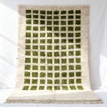 Modern wool rug featuring geometric green grid design on ivory background with tasseled edges