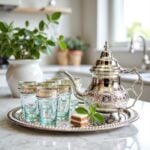 Silver engraved beldi tea set with natural aqua glass cups on a white marble countertop in a modern kitchen