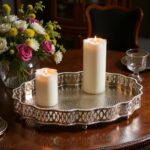 Hammered silver tray styled with white pillar candles and fresh flower arrangement on white surface